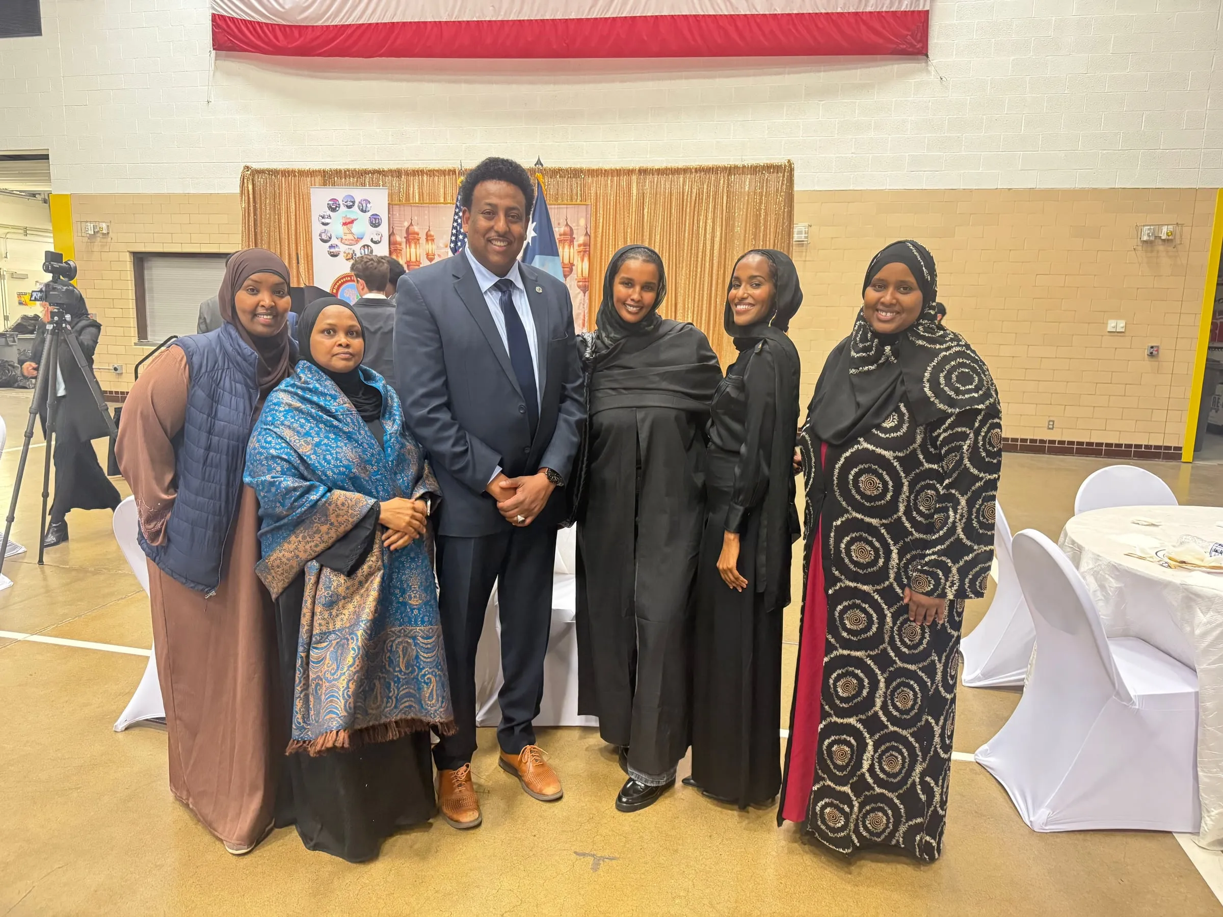 Maangaar Voices members stand with a man in a dark suit at a community gathering.