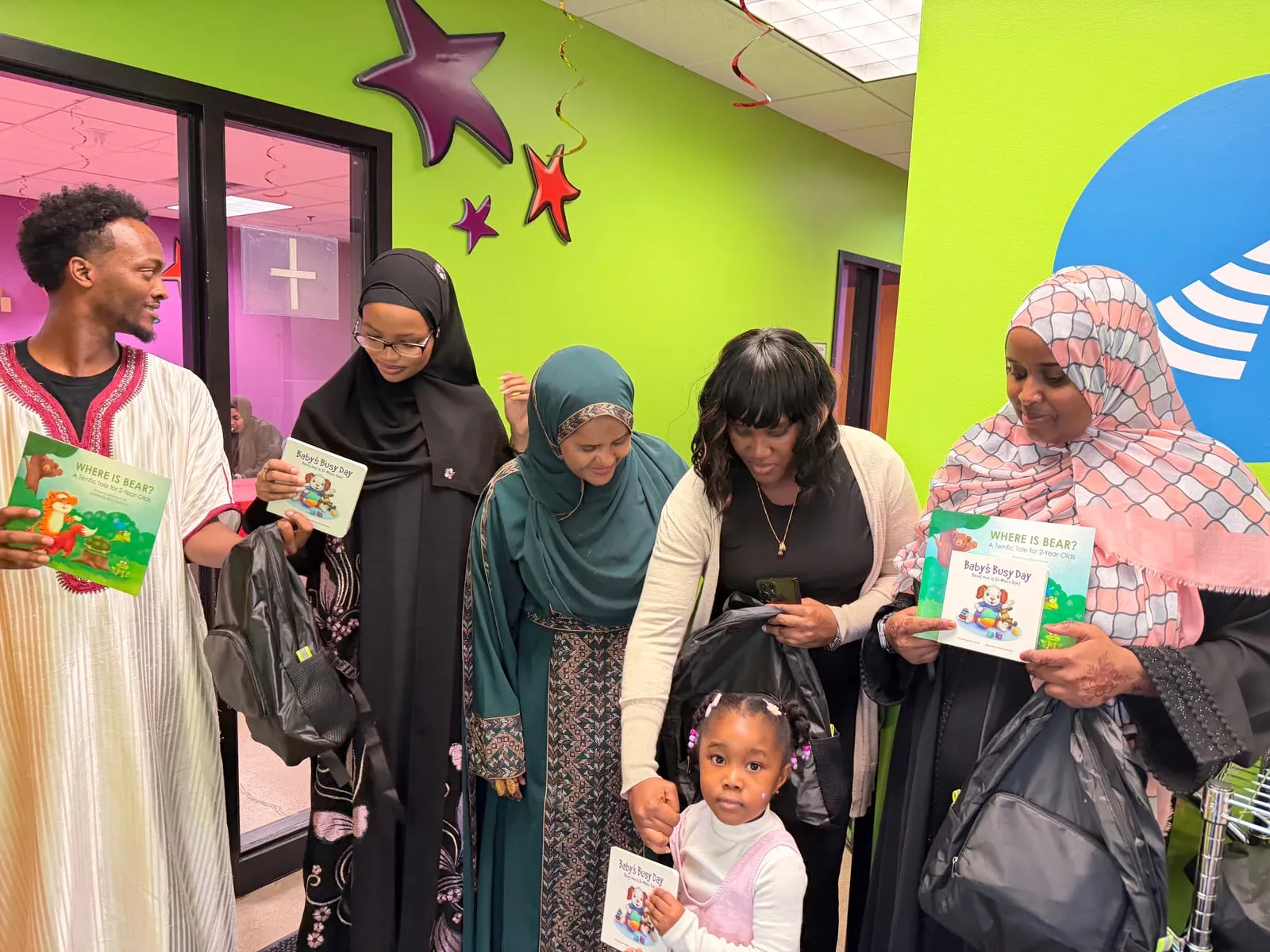 Volunteers hold up sensory backpacks and Help Me Grow picture books at Pump It Up.