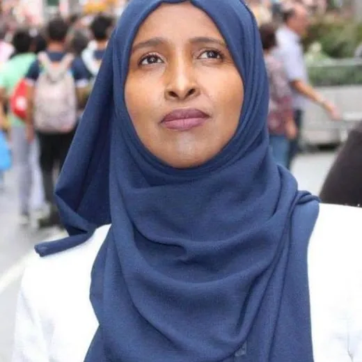 Portrait of Abwaanad Ubah Haldhaa-Warsame in a navy hijab, on a busy street.