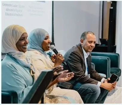 Three panelists share a laugh during a summit discussion.