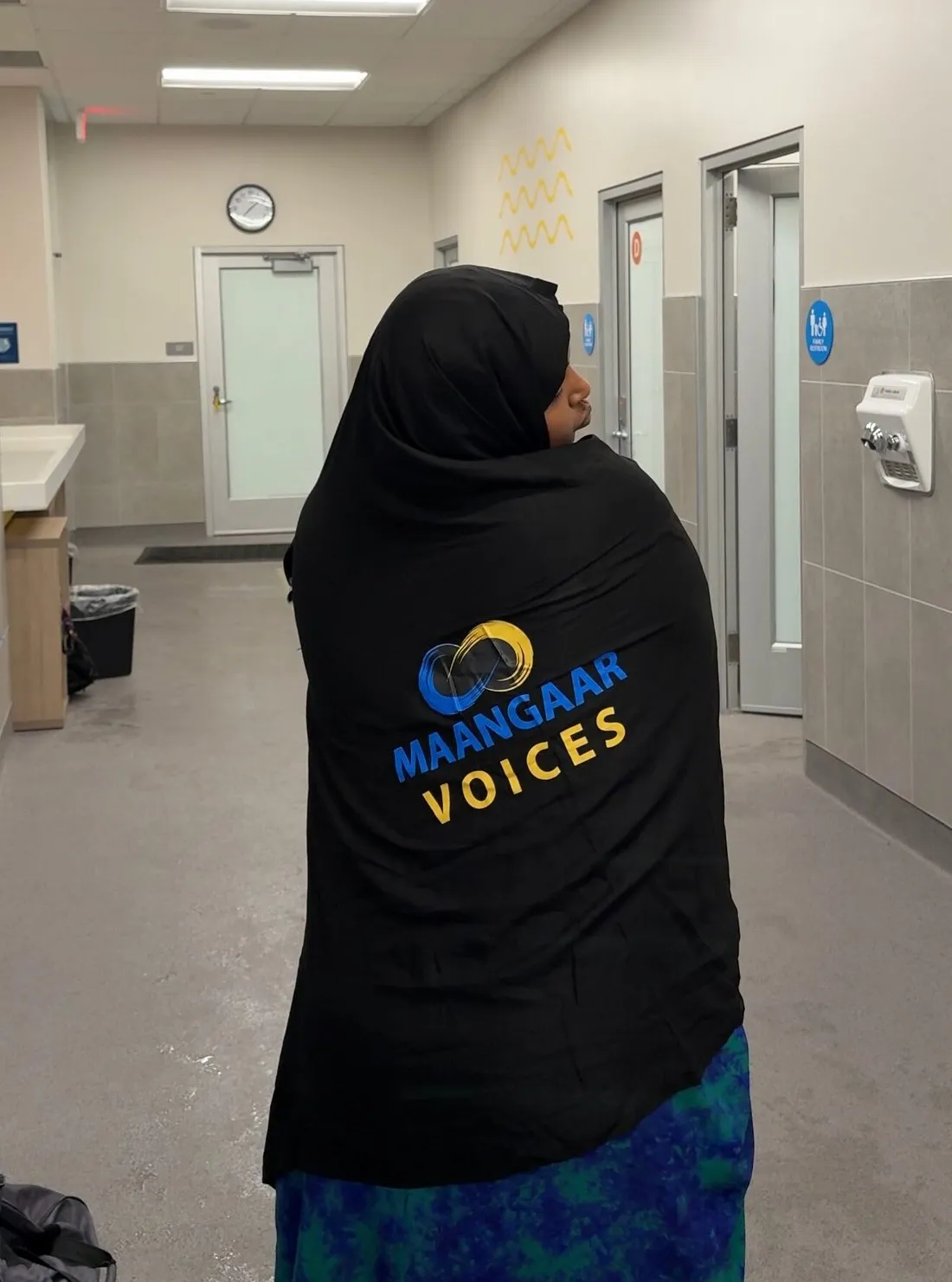 A participant wearing a Maangaar Voices hoodie walks toward the pool entrance at FOSS Swim School.