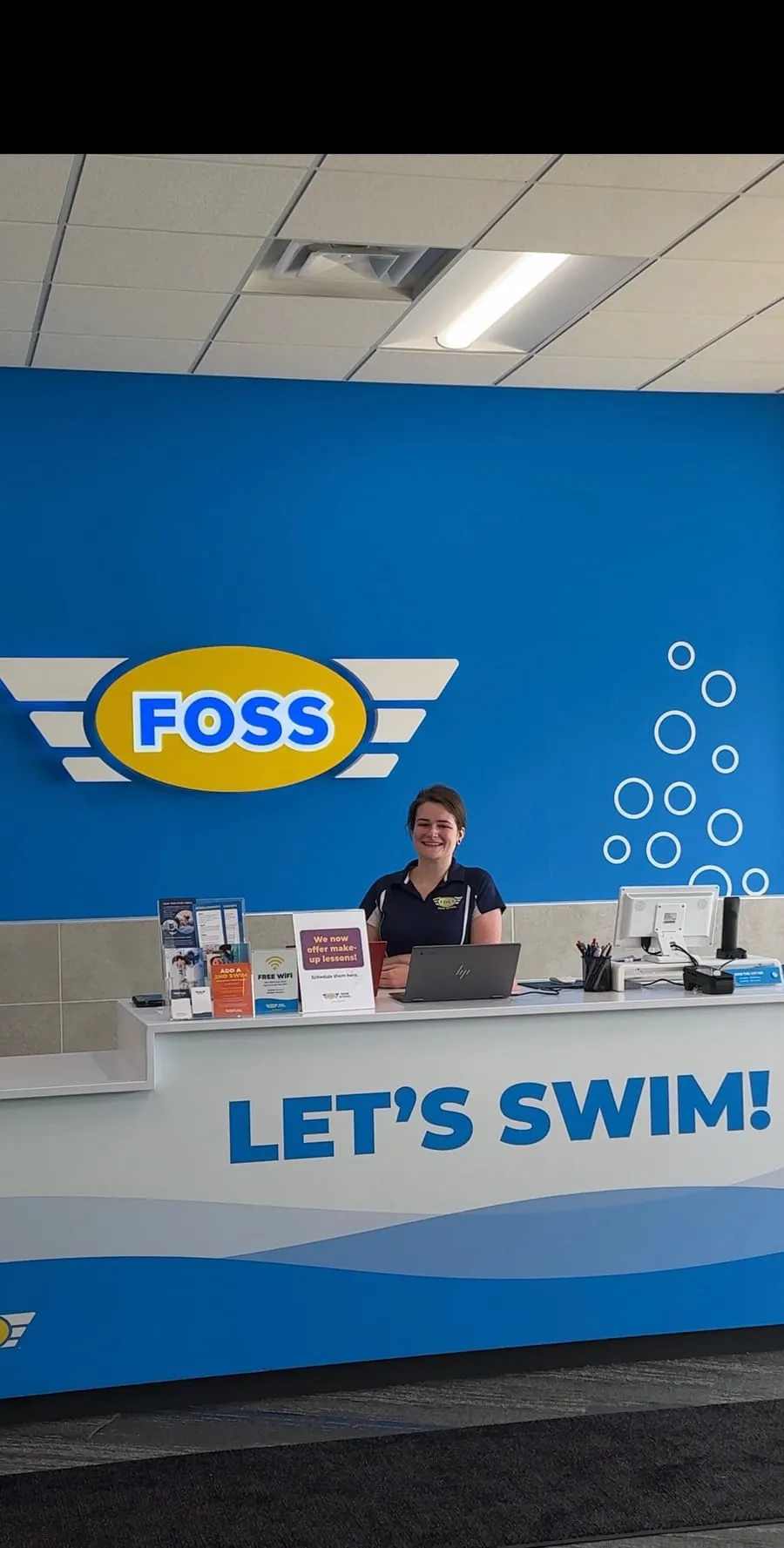 The FOSS Swim School front desk with a “Let’s Swim!” sign.