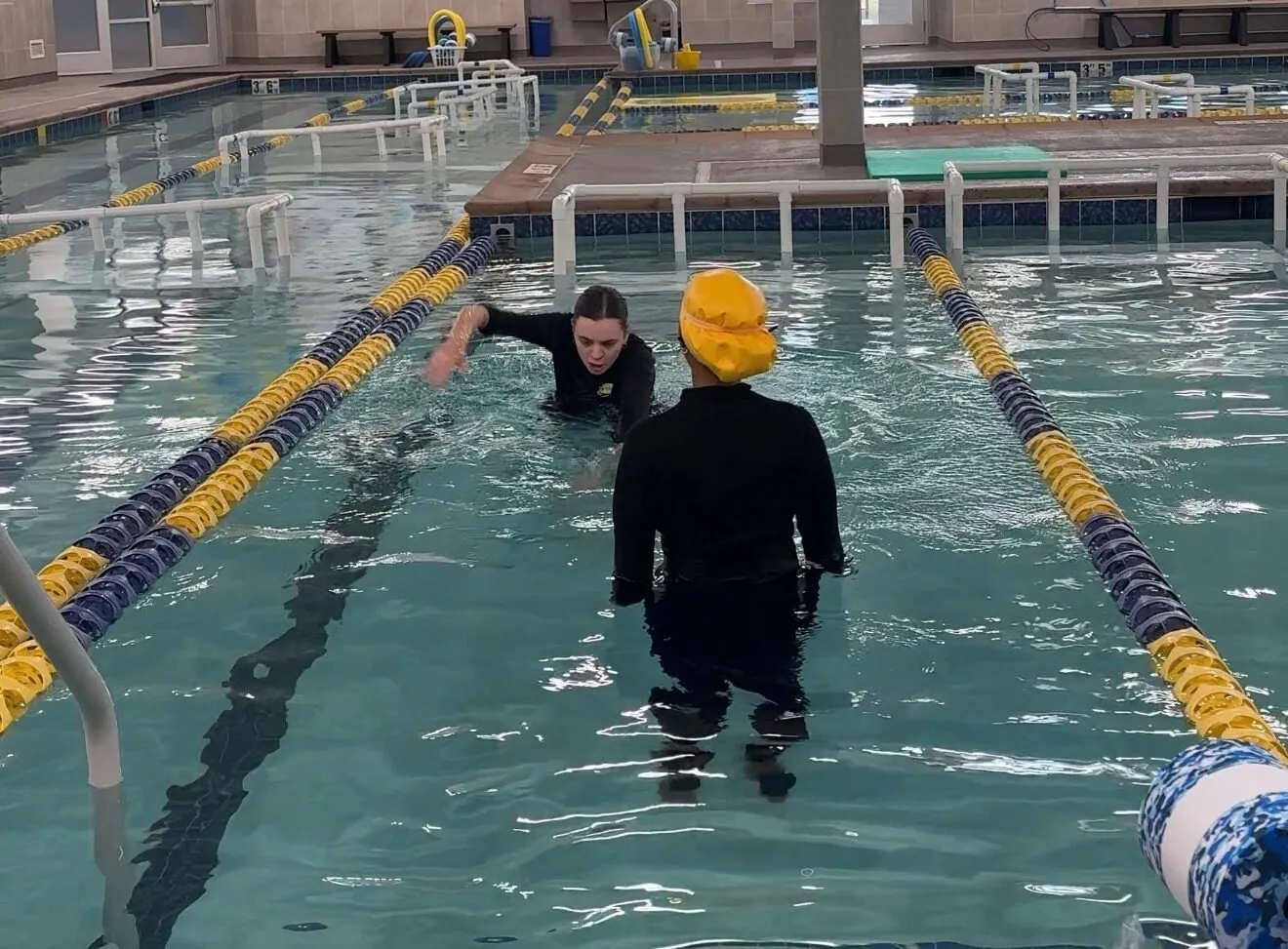 An instructor and a participant in the pool during a lesson.